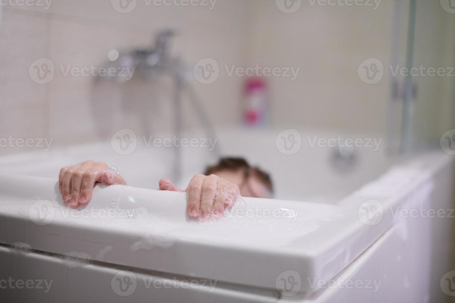 niña en el baño jugando con espuma de jabón foto