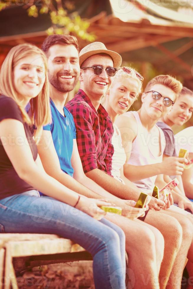 friends enjoying watermelon while sitting on the wooden bridge photo