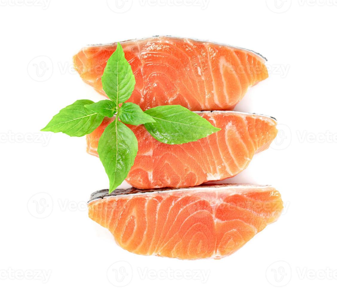 Piece of fresh salmon fillet sliced with leaf basil isolated on white background photo