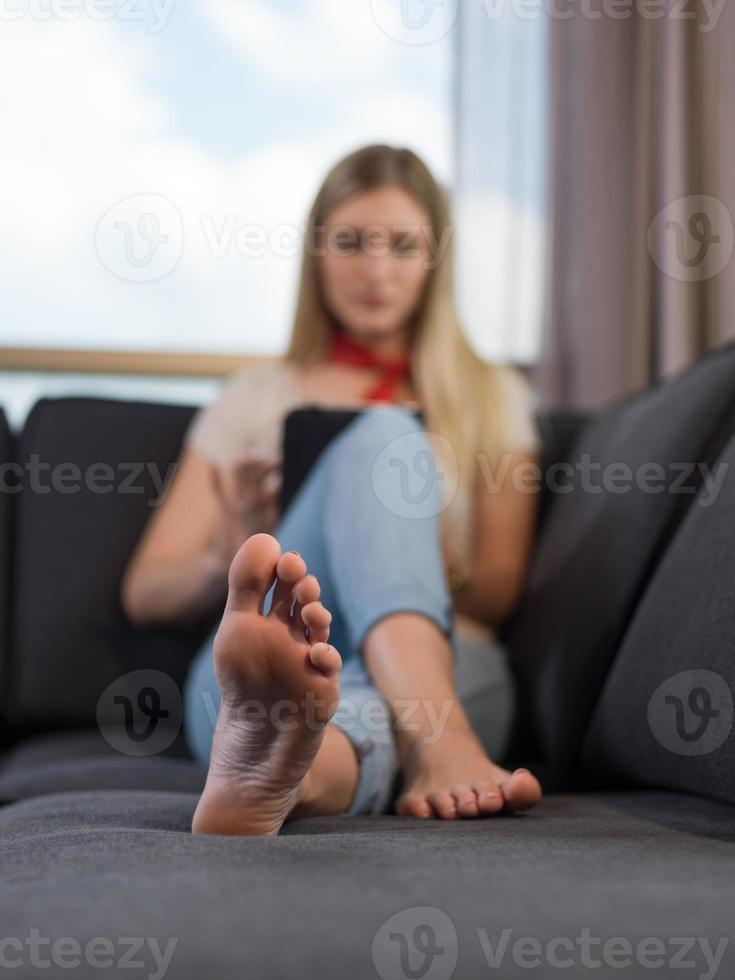 young woman on sofa at home surfing web photo