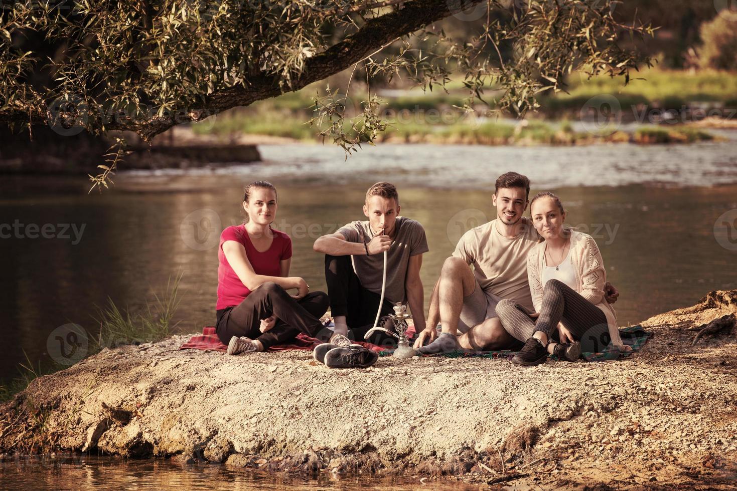 friends smoking hookah on the river bank photo