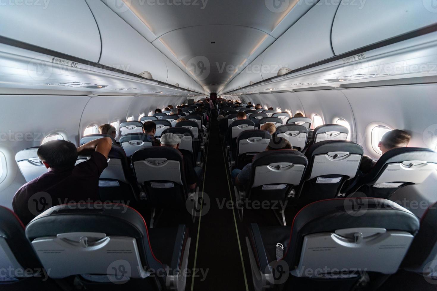 Airplane cabin seats with passengers. Economy class of new cheapest low-cost airlines without delay or cancellation of flight. Travel trip to another country. photo