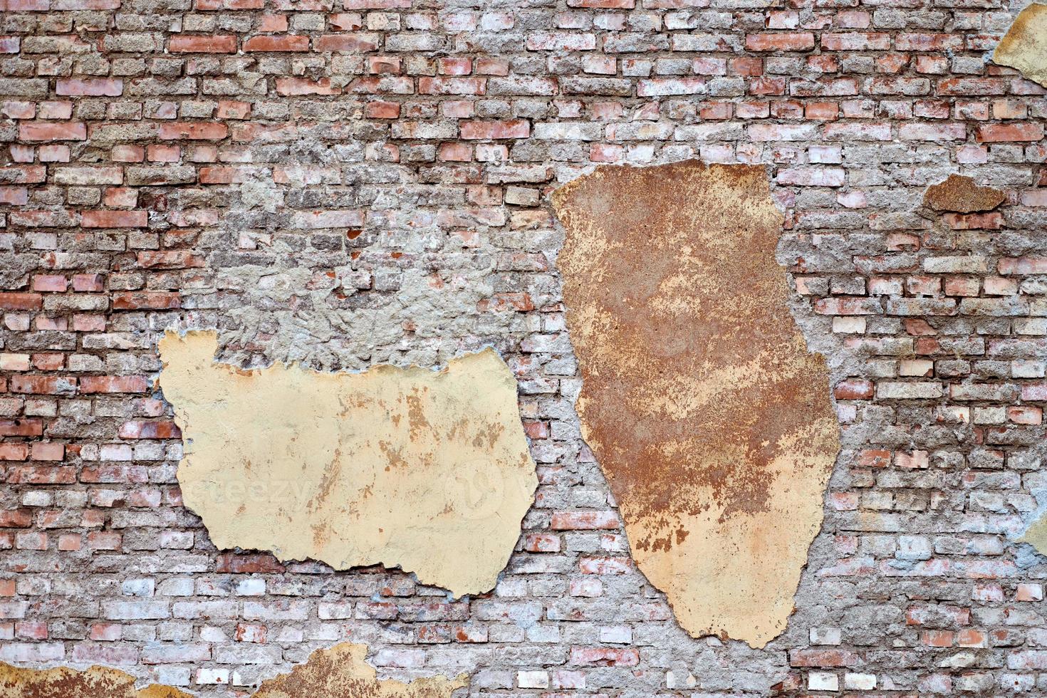 Old brick wall with broken stucco and plaster photo