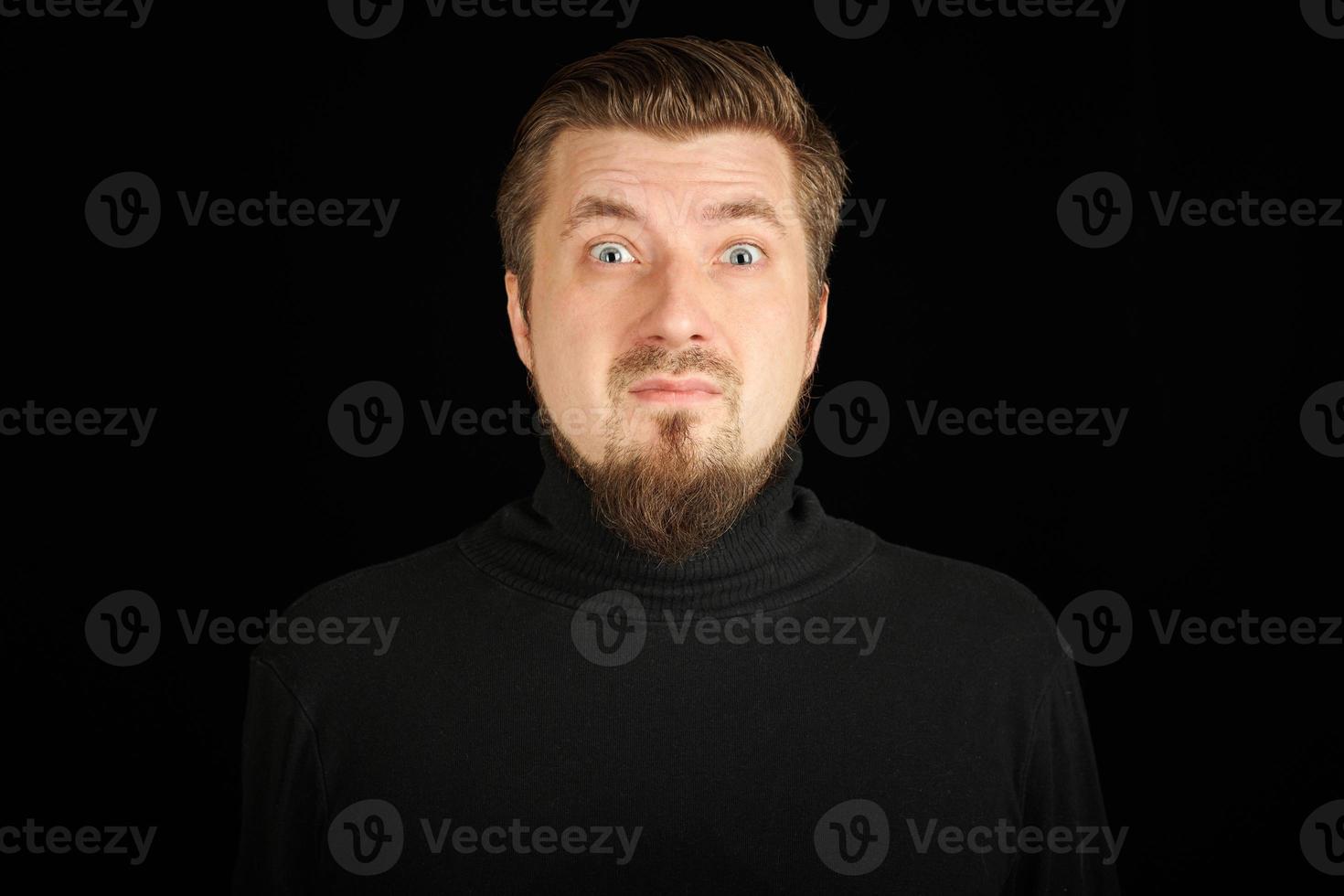 Surprised bearded young guy in black polo neck sweater. photo