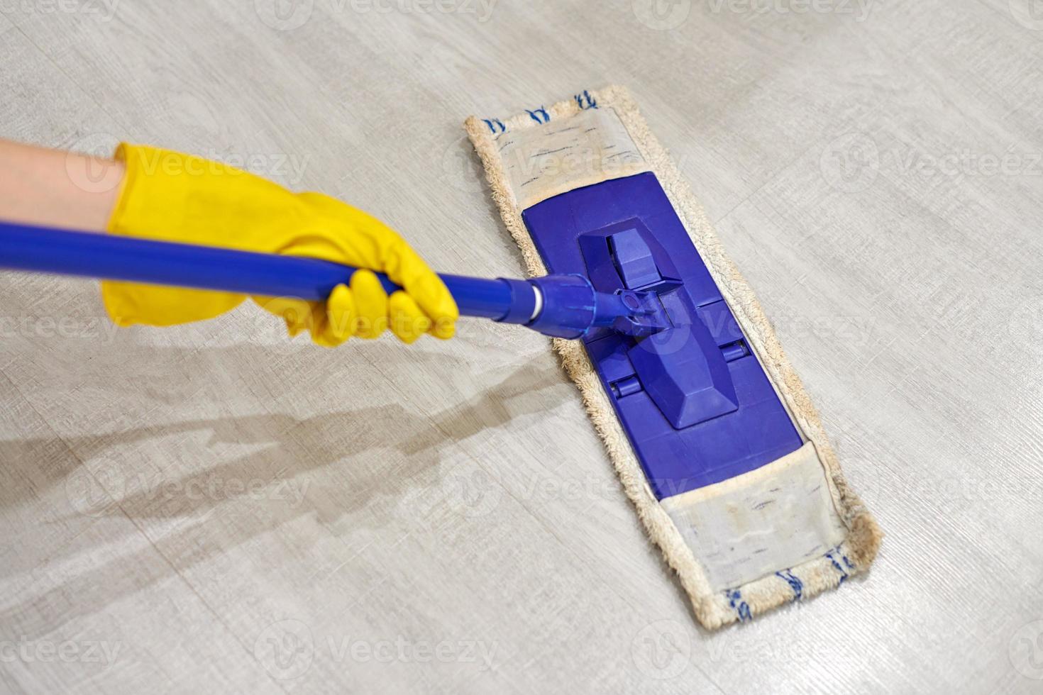 Girl in protective gloves cleaning floor using flat wet mop. photo