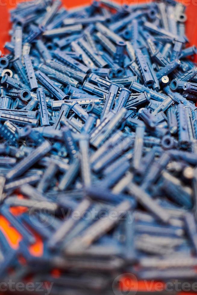 Plastic blue dowels on red background, wall plugs for fixation and installation, close up, top view photo