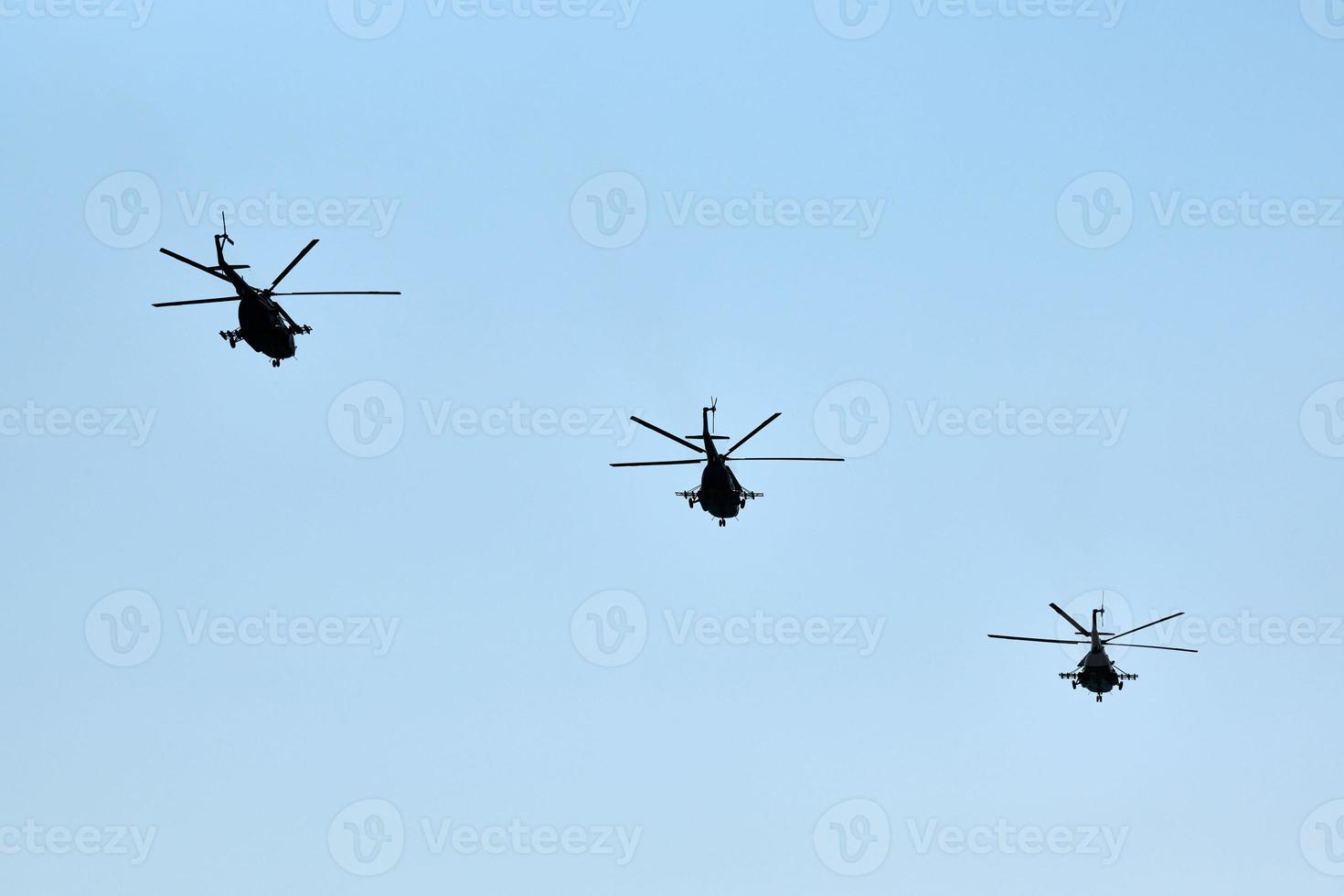 Military helicopters flying in blue sky performing demonstration flight, aerobatic team, air show photo
