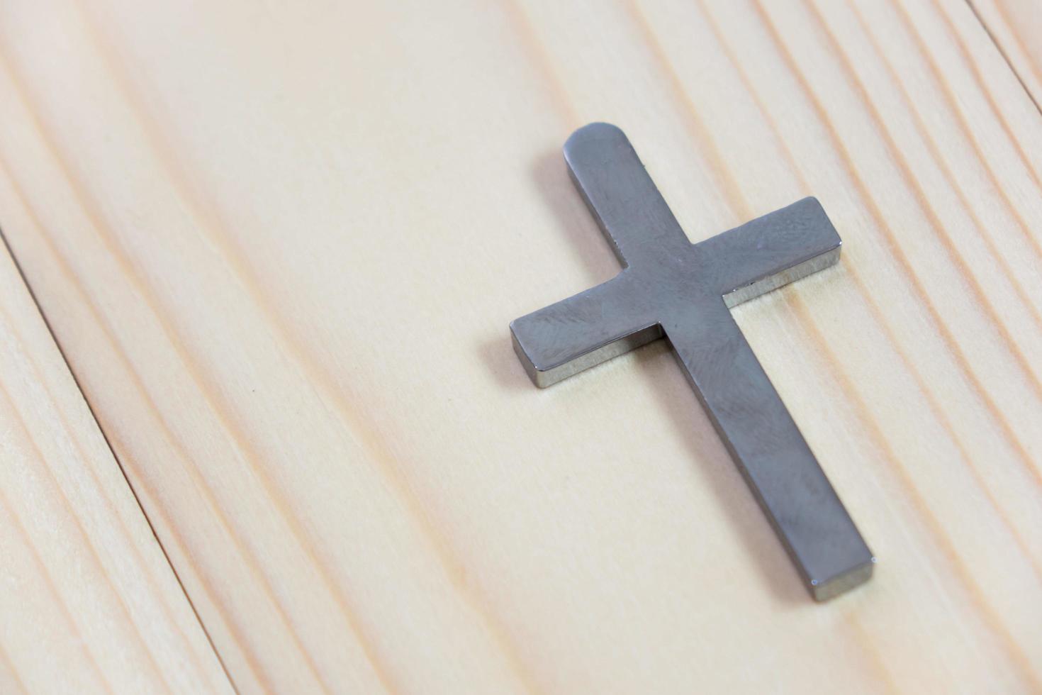 Necklace with silver cross on wooden table photo