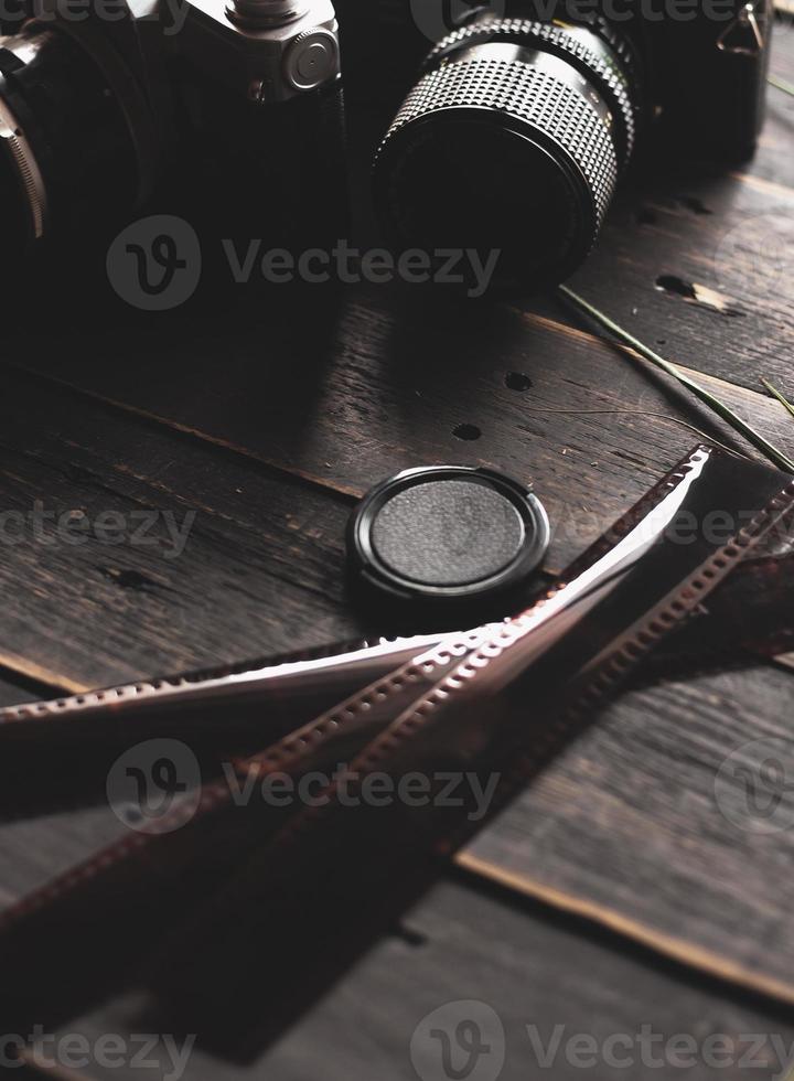 Retro film camera and negative film on a black wooden table photo