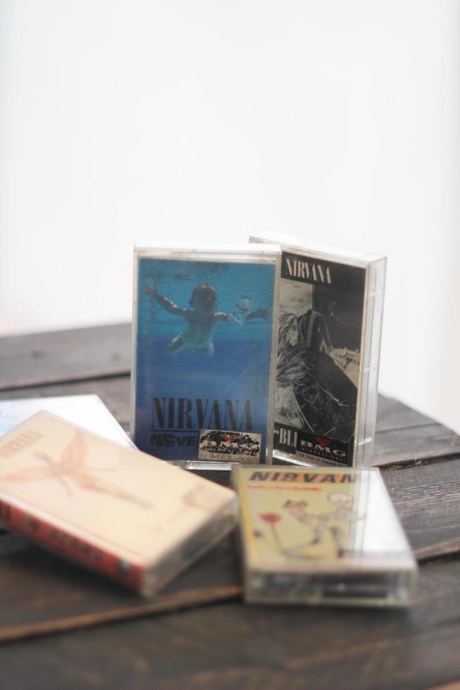 Bangkok, Thailand  January ,22 2022  90's cassette tapes of Nirvana Albums Incesticide, Nevermind, Bleach, From The Muddy Banks of The Wishkah on a black wooden floor. photo