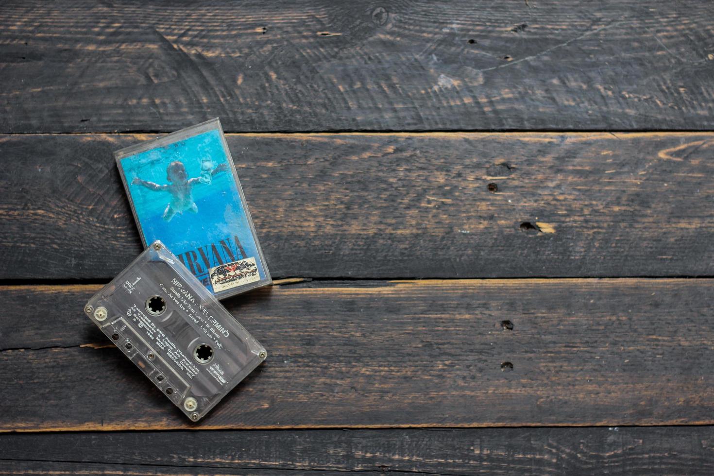 Bangkok, Thailand  January ,22 2022  90's cassette tapes of Nirvana Album Nervermind on a black wooden floor. photo