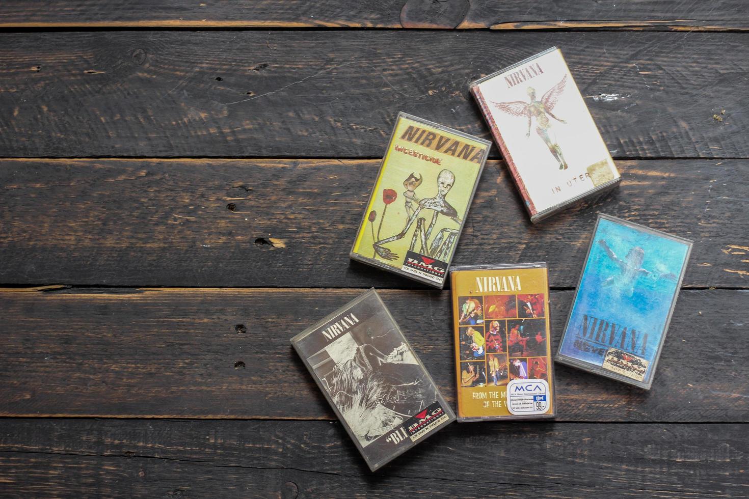 Bangkok, Thailand  January ,22 2022  90's cassette tapes of Nirvana Albums Incesticide, Nevermind, Bleach, From The Muddy Banks of The Wishkah on a black wooden floor. photo