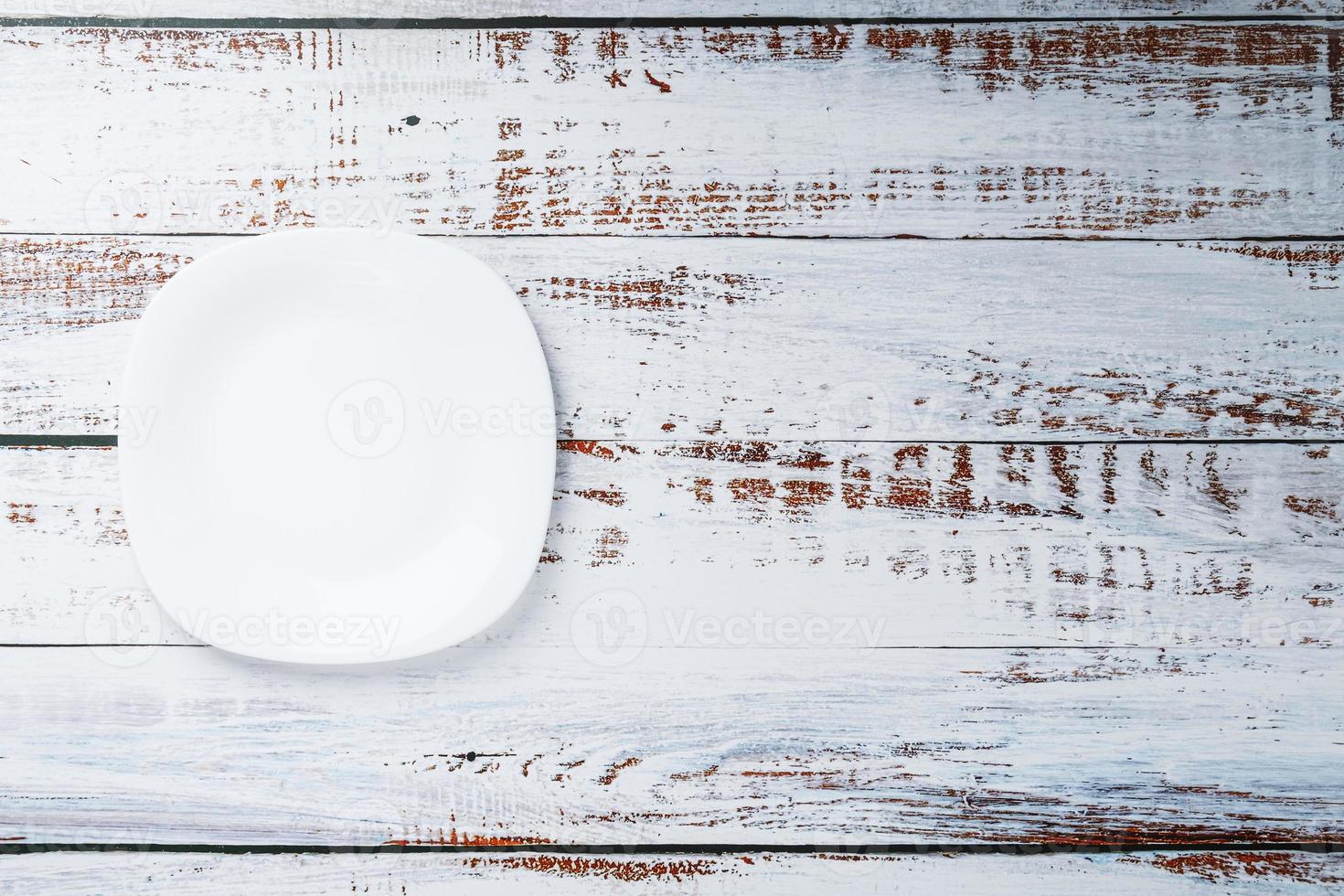 An empty round white plate on a blue wooden table. photo