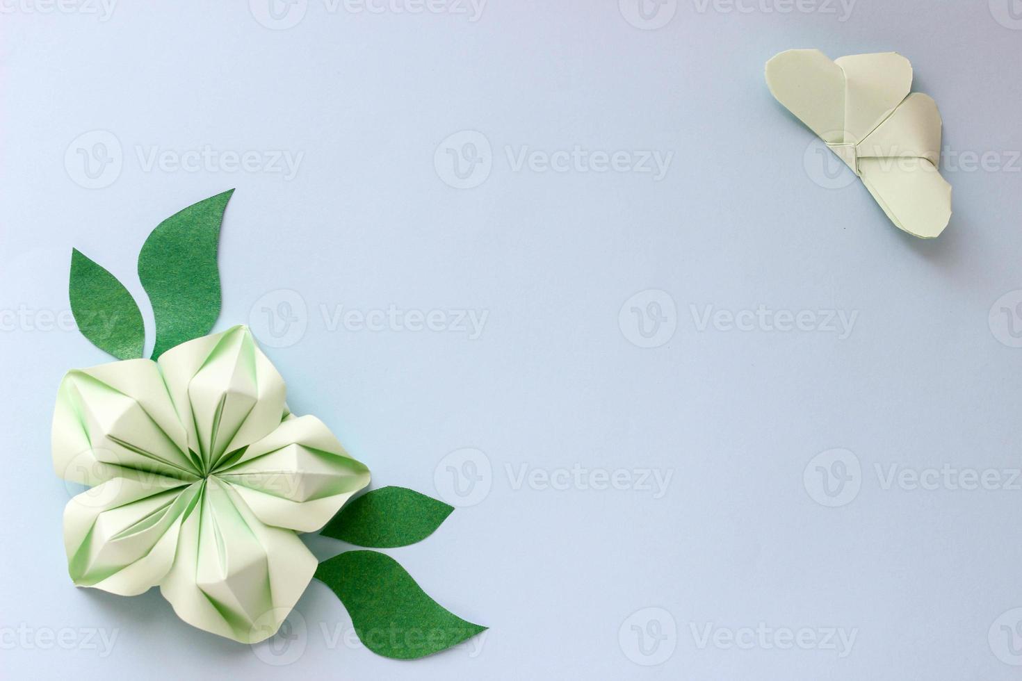 Origami paper background with butterfly, flower and leaves. With place for text. Origami composition. Paper craft photo