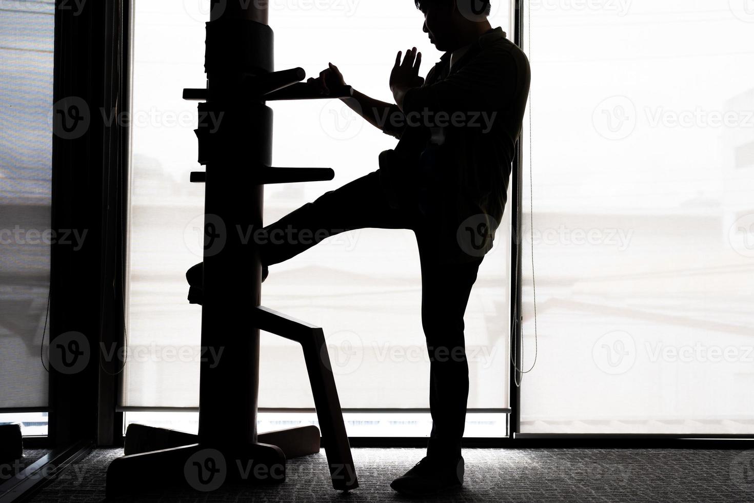 Silhouette of a fighter Wing Chun and wooden dummy on a background. Wing Chun Kung Fu Self defense photo