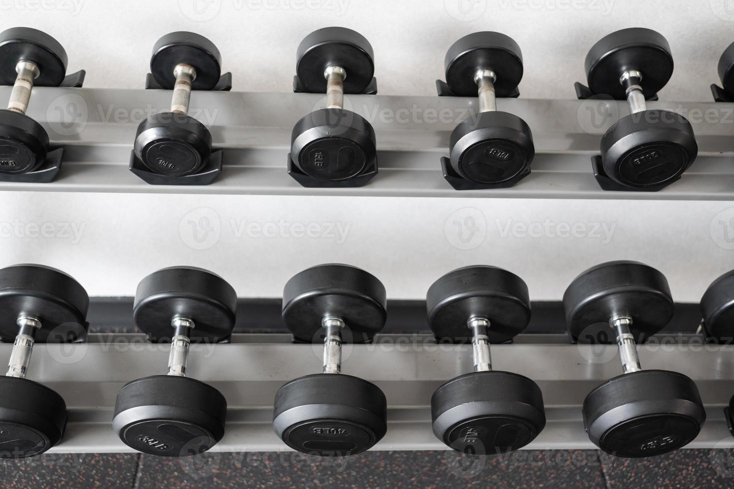 Stand with dumbbells. Sports and fitness room. Weight Training Equipment. Black dumbbell set, many dumbbells on rack in sport fitness center photo