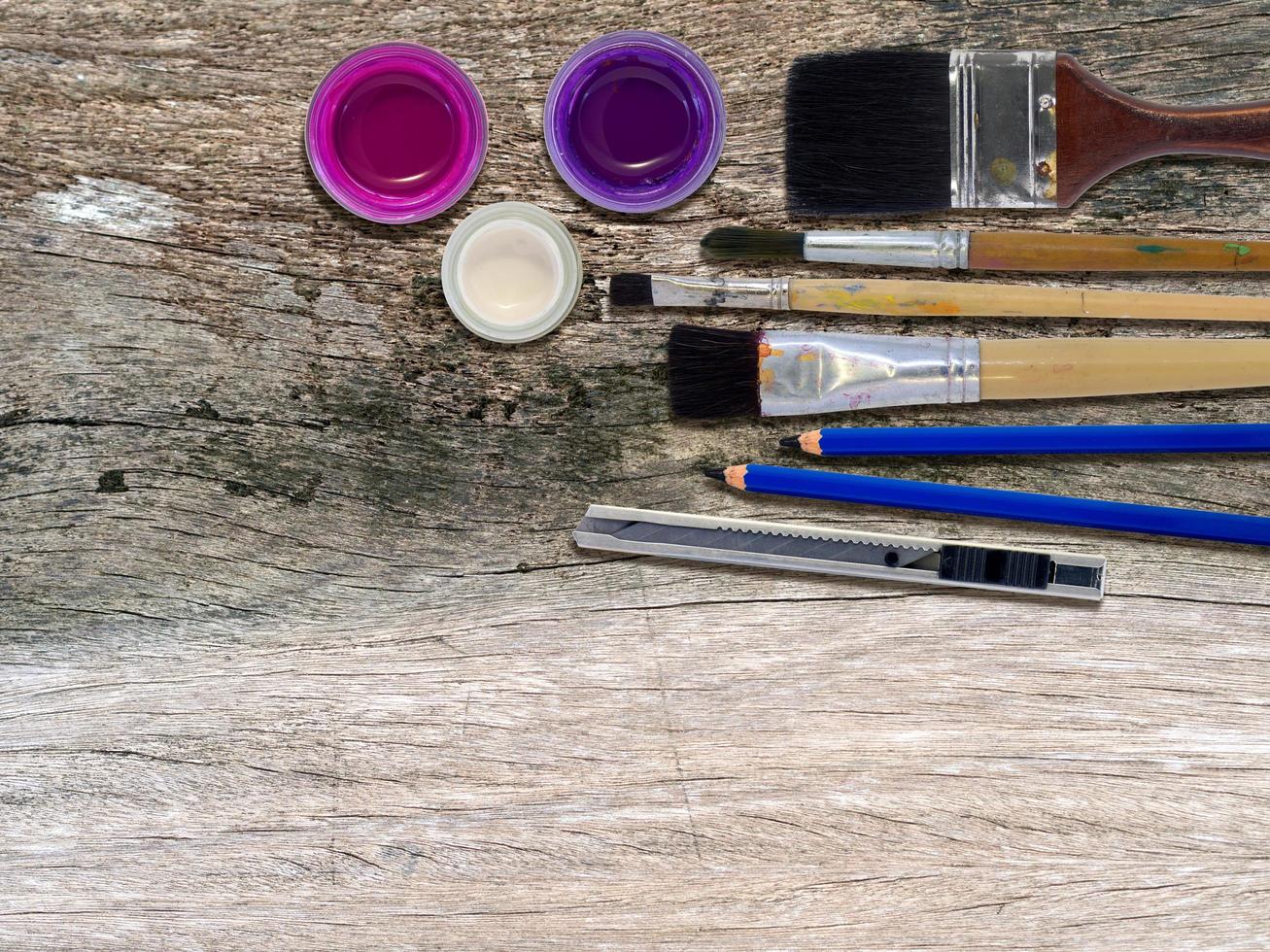 Top view of poster color bottles and brush on old wooden table. photo