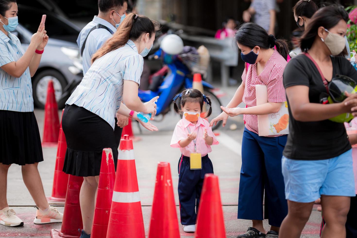 Bangkok Thailand-15 July 20. Asian girl wash their hands with alcohol gel before entering the school door with teachers pressing the cleaning gel. Including everyone will pass through the school gate. photo