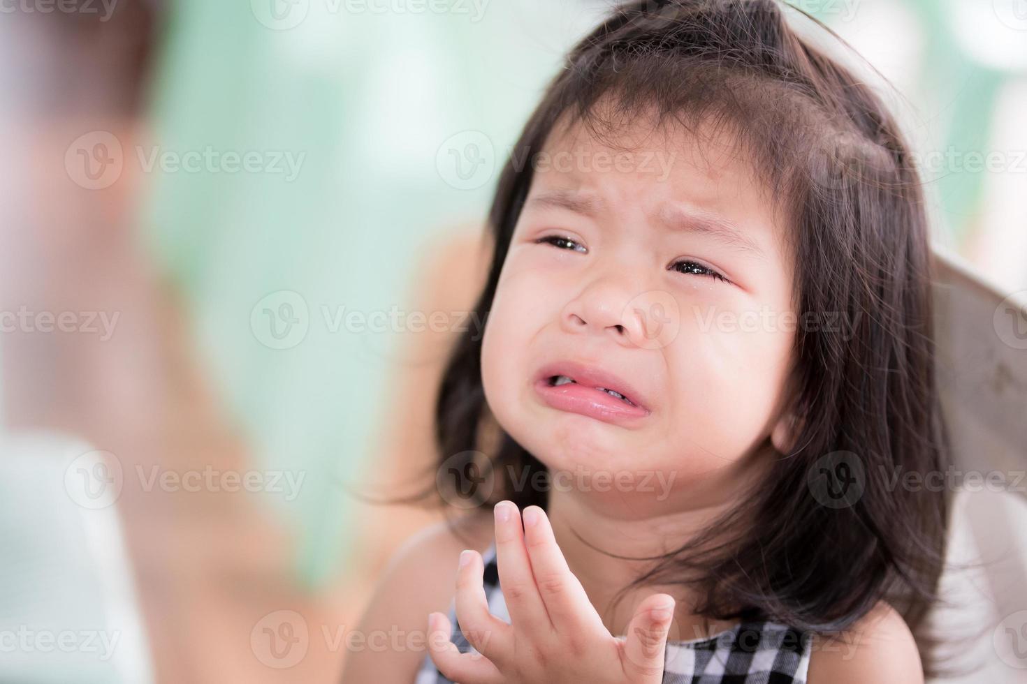 An Asian little child girl is crying, sad tears from being scolded by an adult. Baby kid 3 years old. In the summer temple area. The concept of sadness for young children. photo