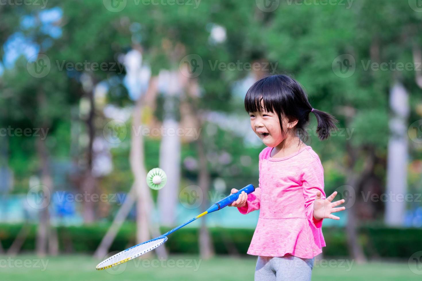 Portrait image child 5 years old. Cute Asian girl having fun playing badminton. Little children enjoy playing outdoor sports. Summer or spring season. Kid show excitement about learning new things. photo