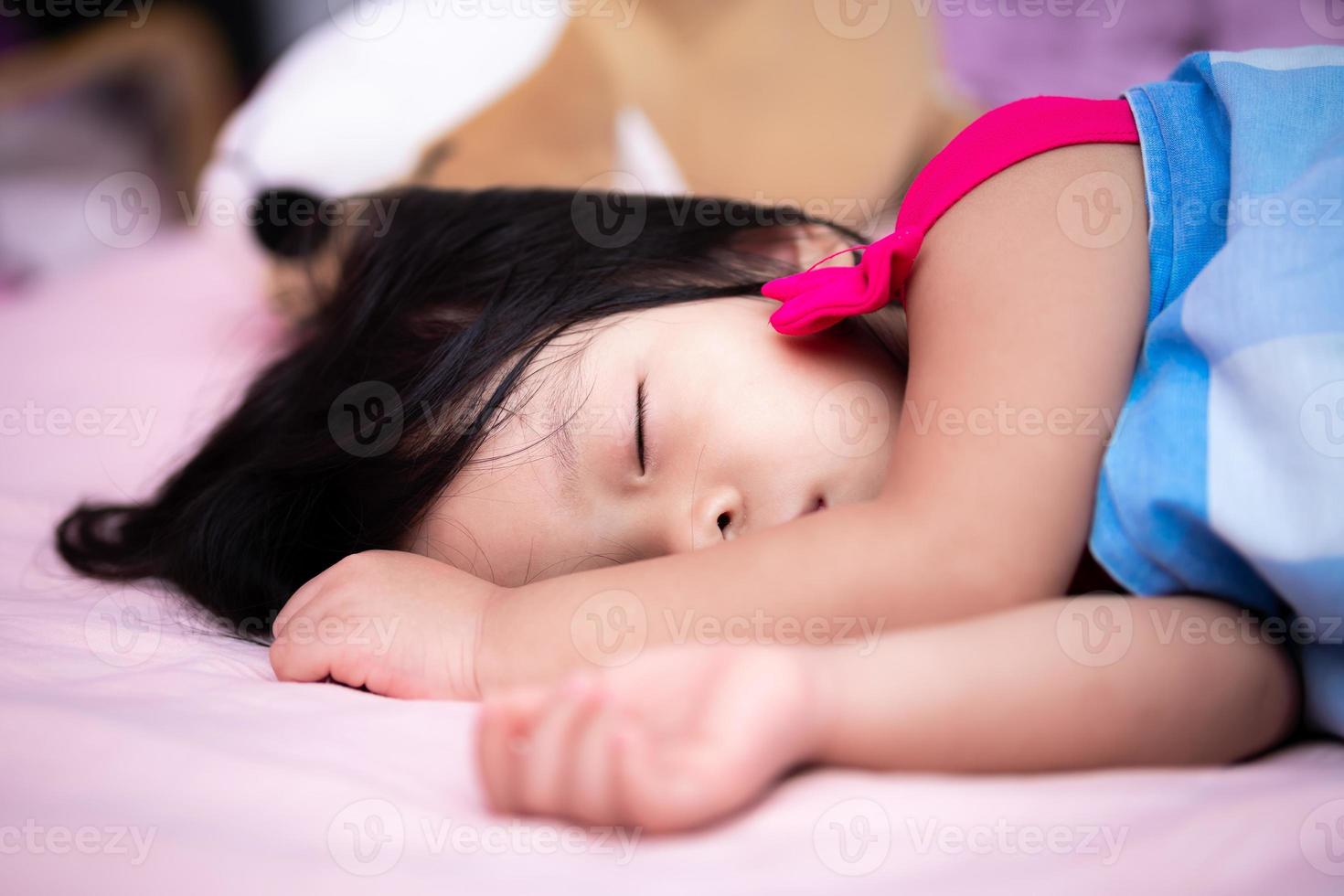 Asian child is sleeping on a pink bed. Kid covers the cloth with a blue blanket. Children sleep sweetly. Adorable children rest and sleep in the afternoon. Baby aged 3 years and 5 month. photo