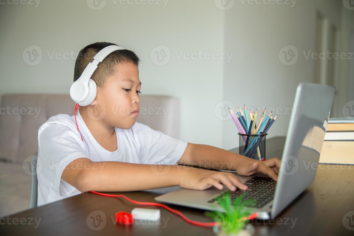 Young student distance learning virtual distance online class on video call virtual lesson, technology studying at home using laptop computer. Parent or tutor teaching child boy with remote education. photo