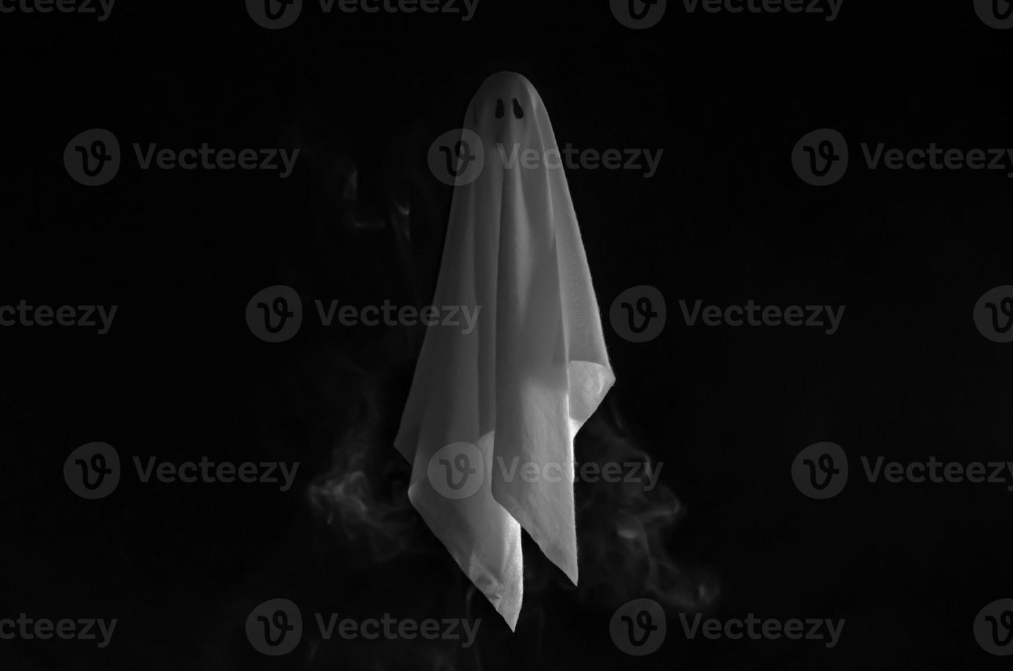 Partial focus of white ghost sheet flying in dark background with smoke. Halloween scary concept. photo
