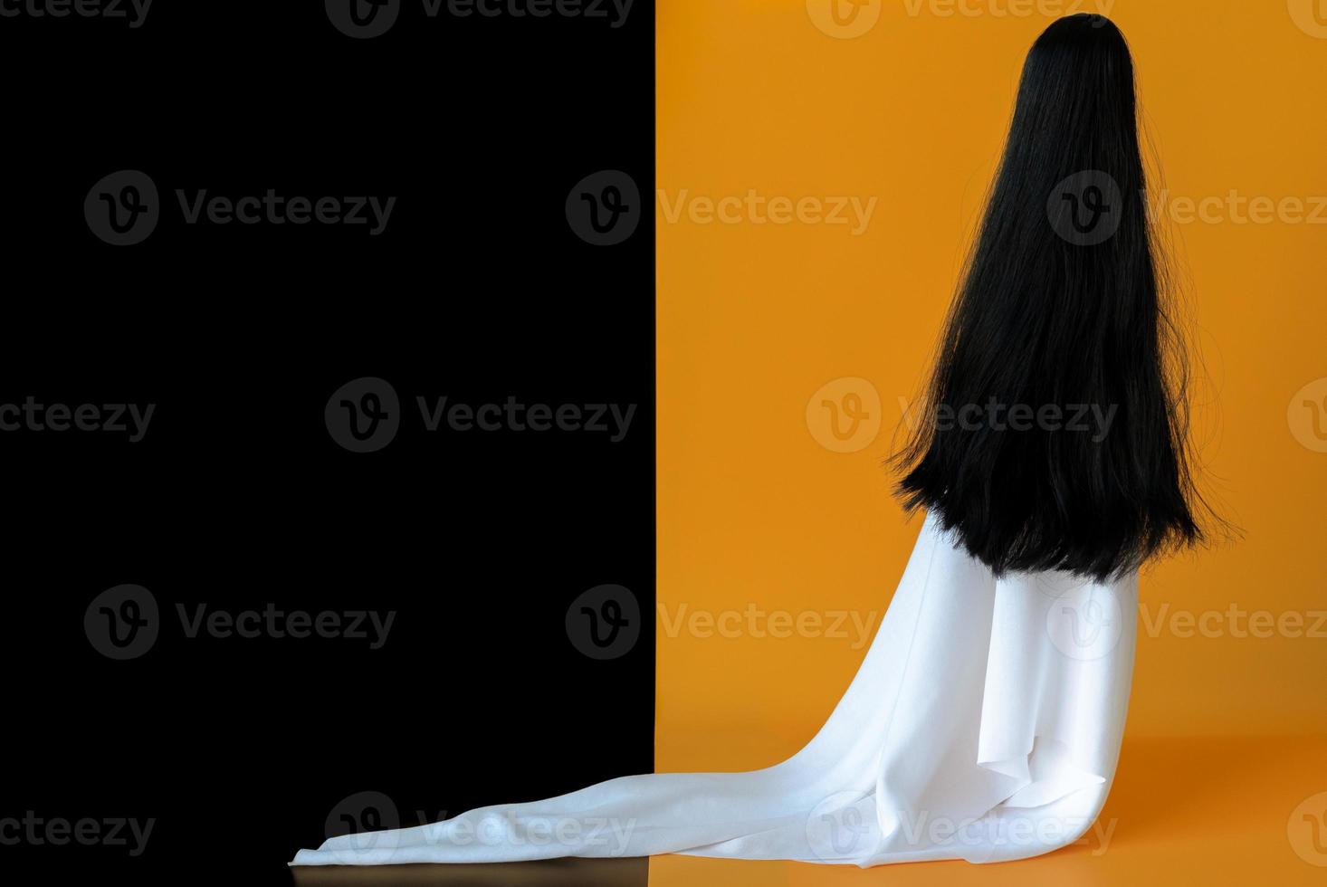 Long hair female ghost with white sheet costume with black and orange background. Minimal Halloween scary concept. photo