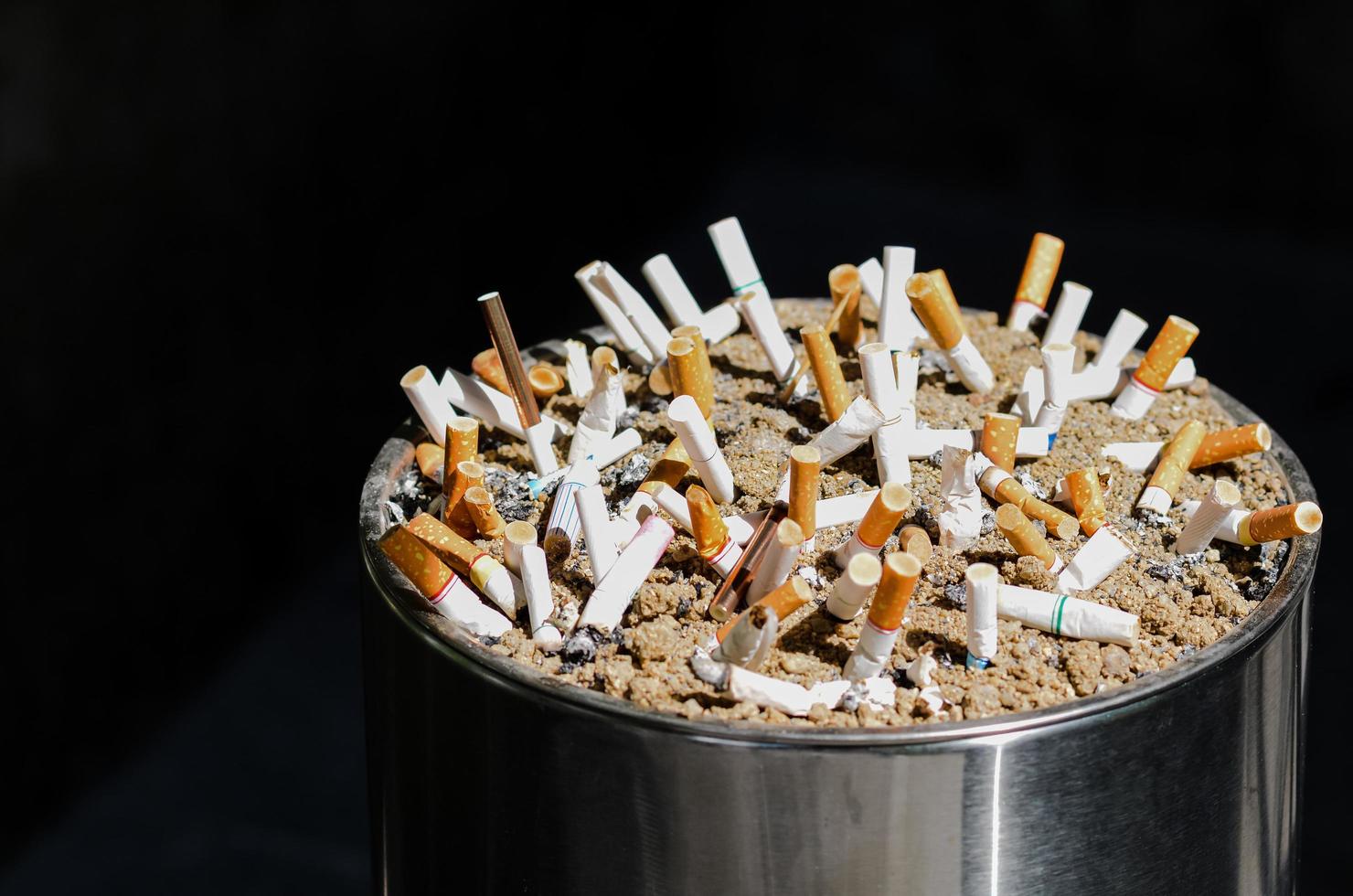 The big ashtray with many focus and blurred cigarettes that smokers only can smoke in the limit smoking area. photo