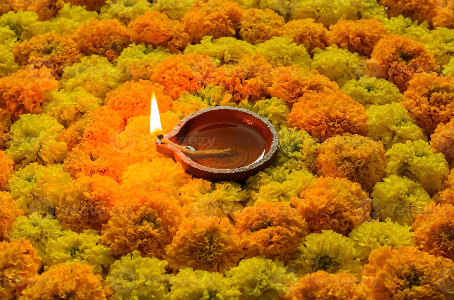 Decorative marigold flower rangoli for Diwali festival with clay diya lamp lit with flame. photo