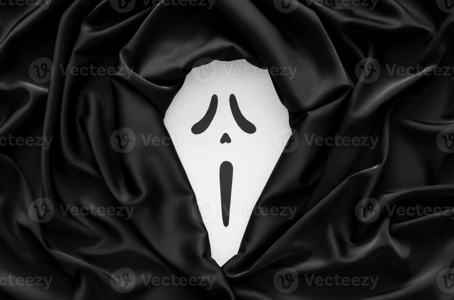 cara fantasma aterradora blanca con tela satinada negra para el concepto de fondo de halloween. foto