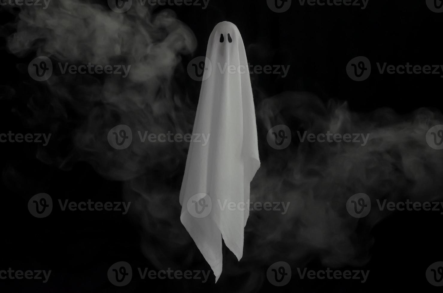 White ghost sheet flying in dark background with smoke. Halloween scary concept. photo