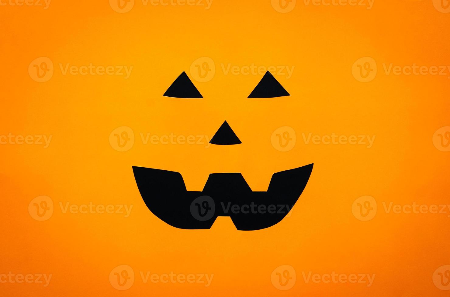 Halloween pumpkin face background from cutting orange and black paper. Minimal halloween concept. photo