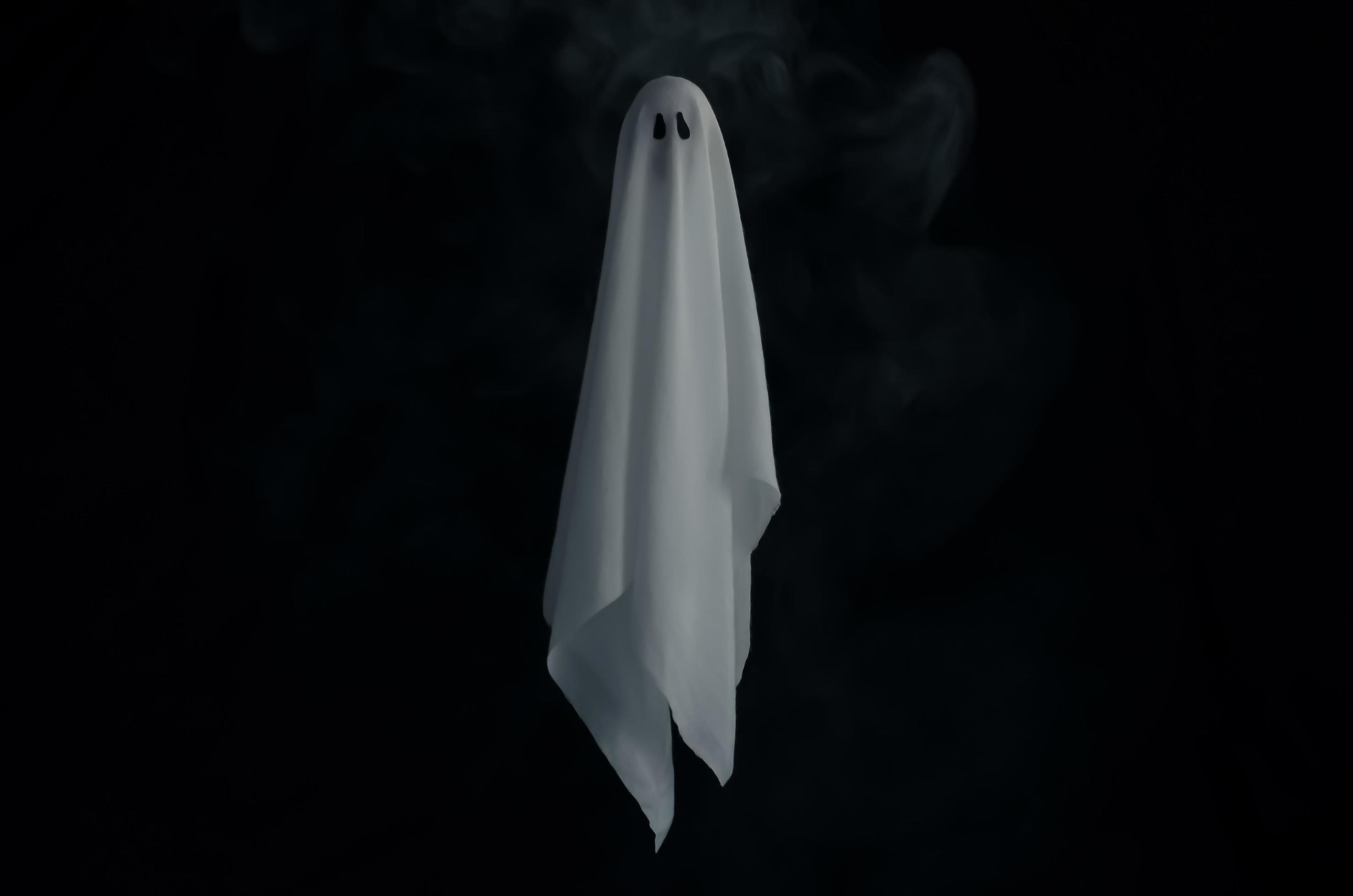 Blurred focus of white ghost sheet in dark background with smoke