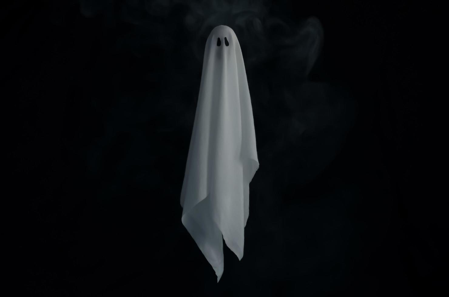 Blurred focus of white ghost sheet in dark background with smoke. Halloween scary concept. photo