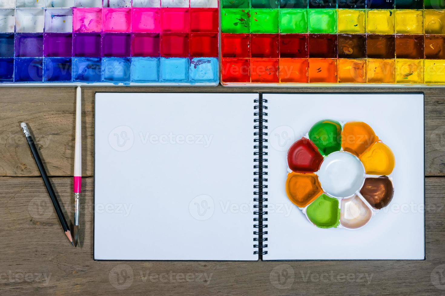 closeup open note book with tray colors on wood background photo