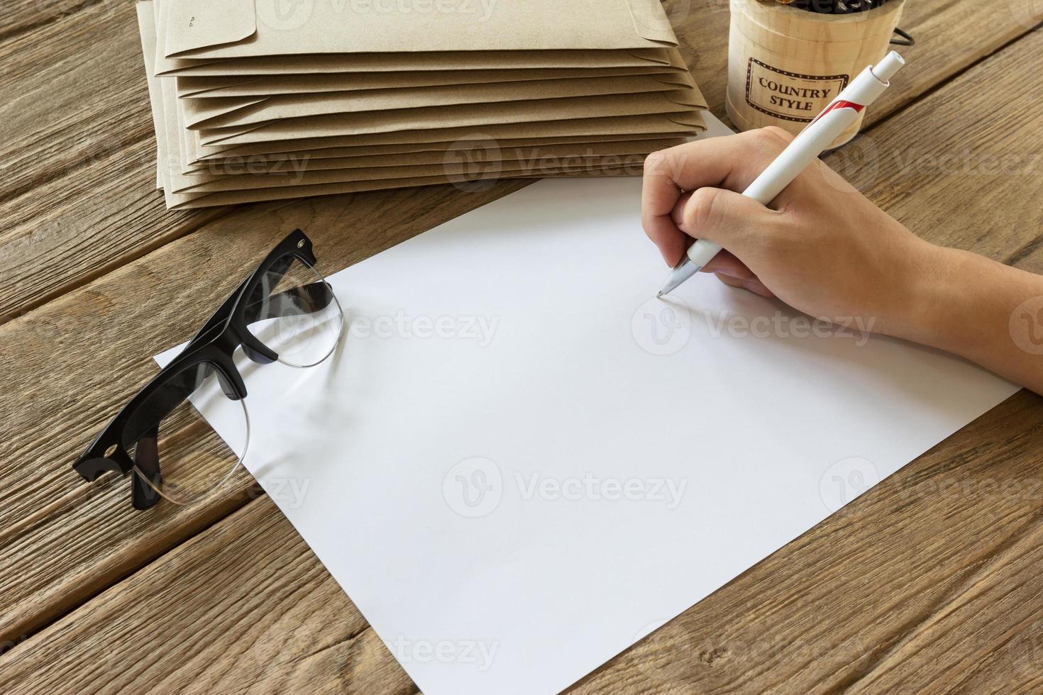 hand holding pen with paper on wooden table photo