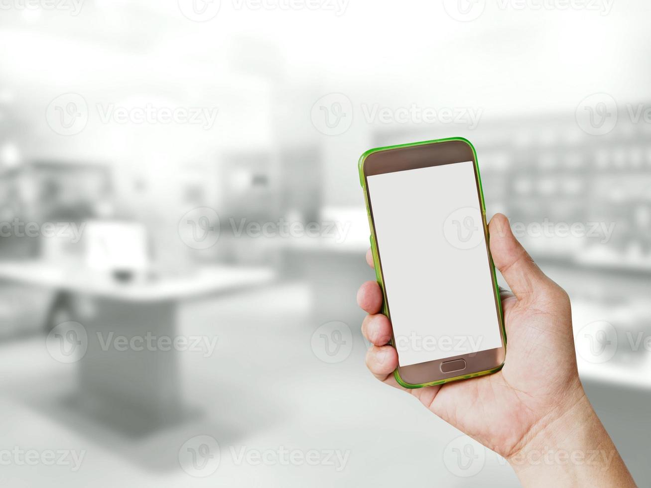 hand holding mobile smart phone with blur phone shop photo