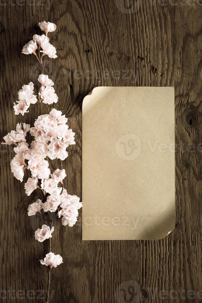 brown paper and pink flowers on wooden background,filter effect. photo