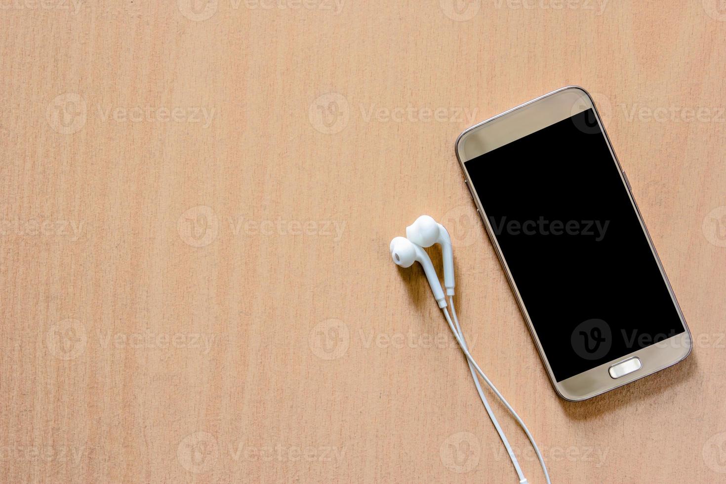 mobile smart phone with earphone on wood background photo
