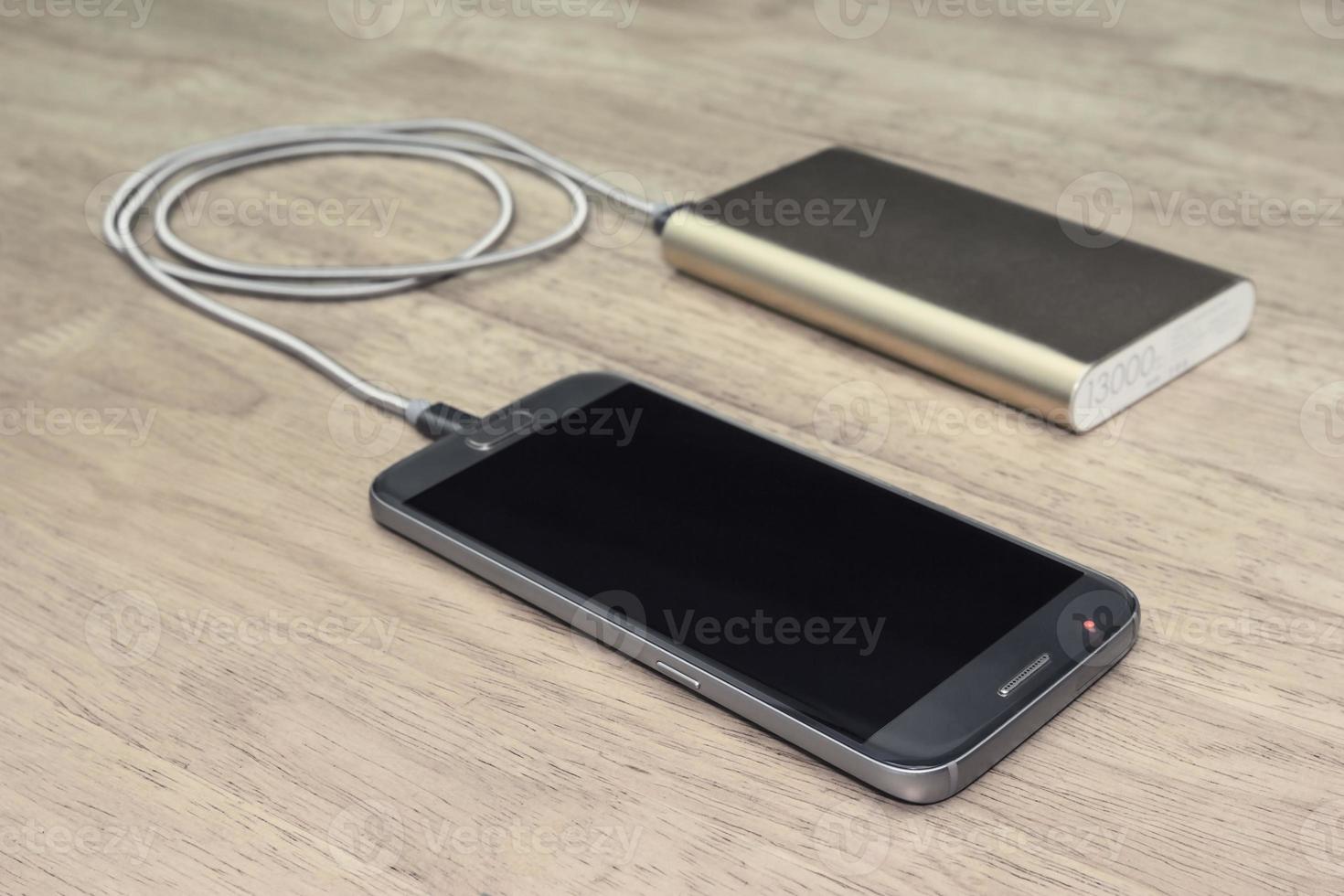 Smartphone charging with power bank on wood background,filter effect photo