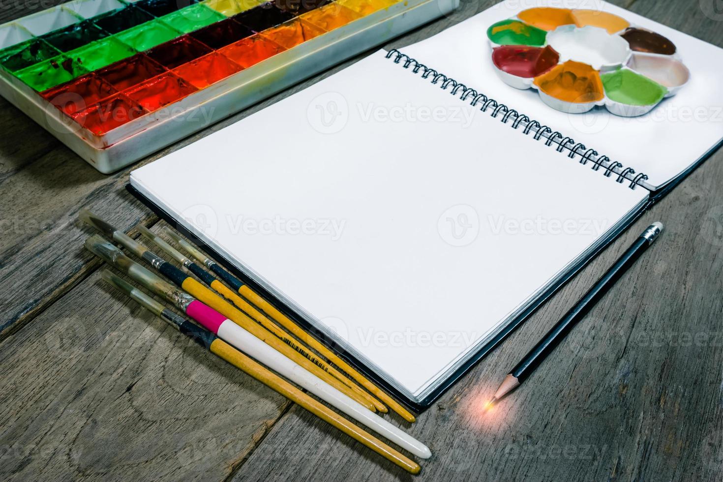 closeup open note book with tray colors on wood background photo