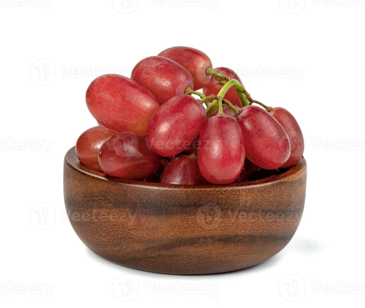 Primer plano de uvas rojas sin semillas con cuenco de madera aislado sobre fondo blanco. foto