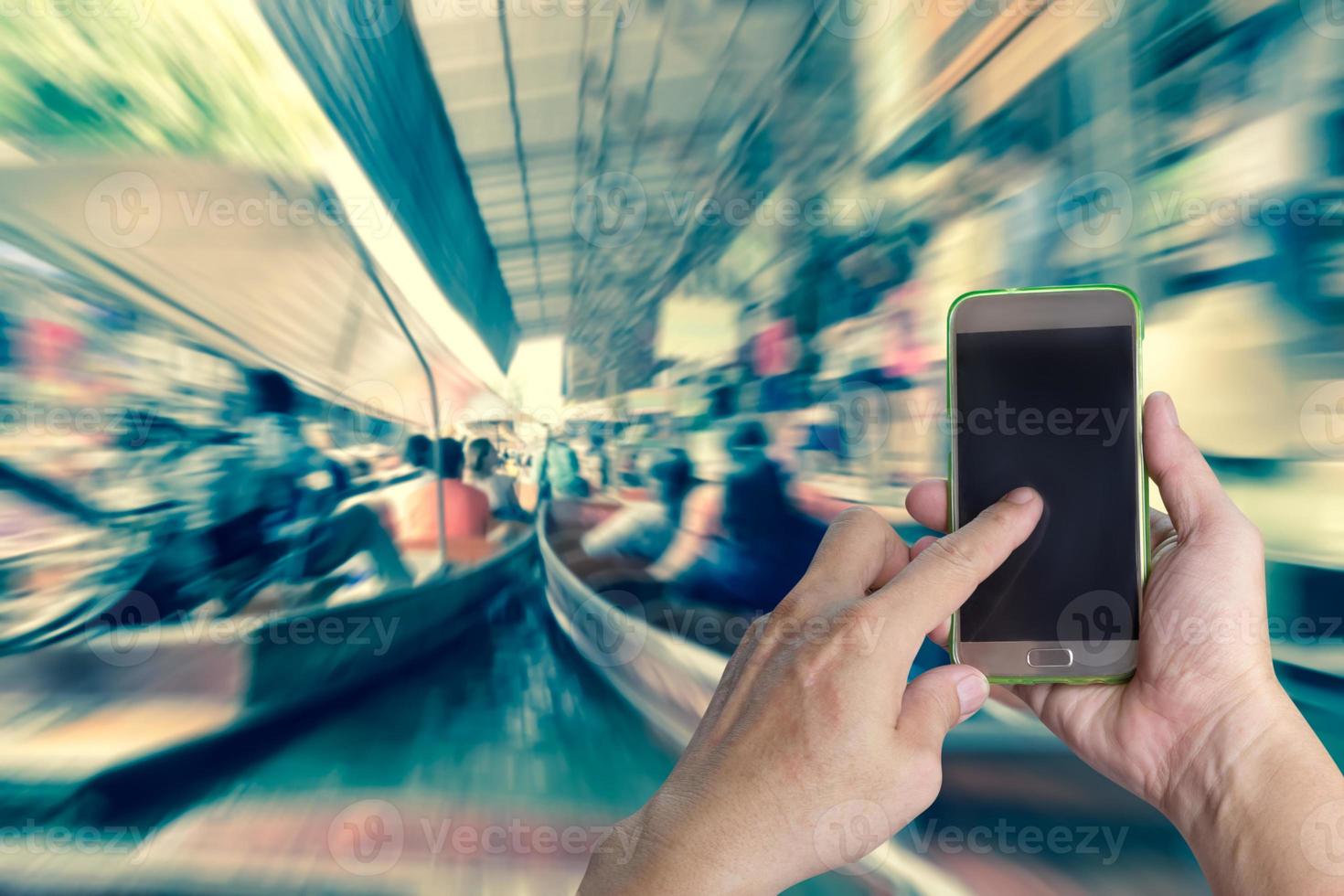 hand holding mobile smart phone with floating market blurred background photo