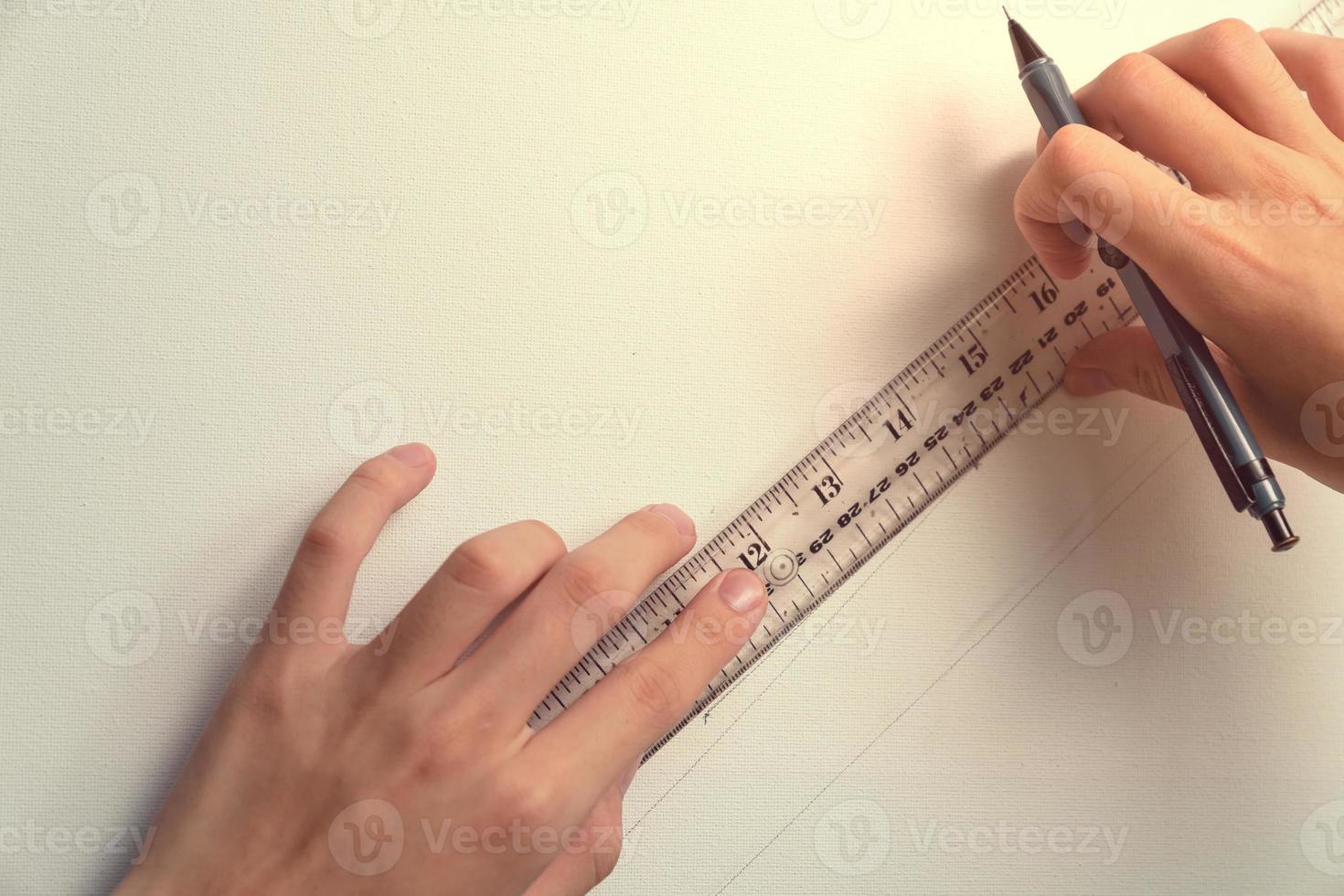 hand holding ruler and clutch-type pencil with canvas background photo