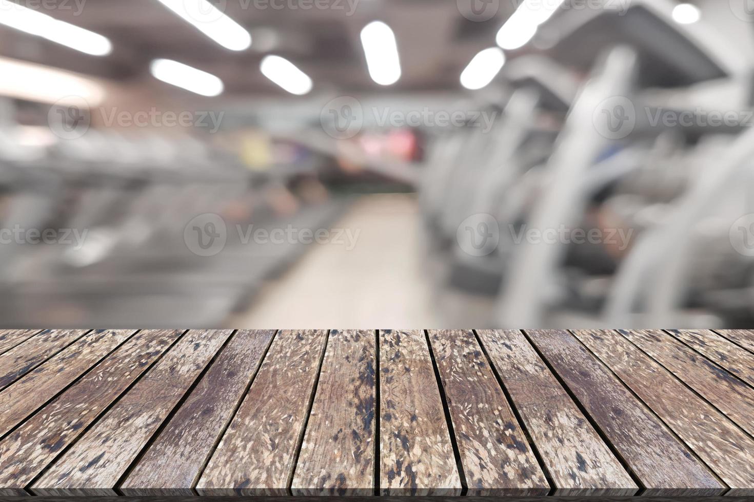 Empty wooden board space platform with blur fitness gym equipment background photo