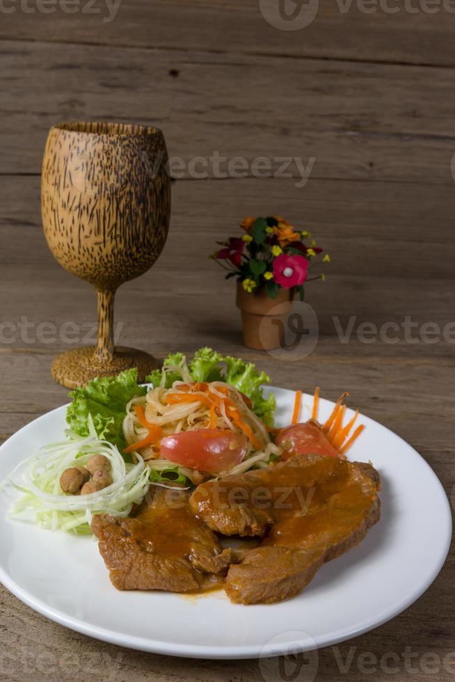 Grilled steak meat with vegetable salad on wood background photo