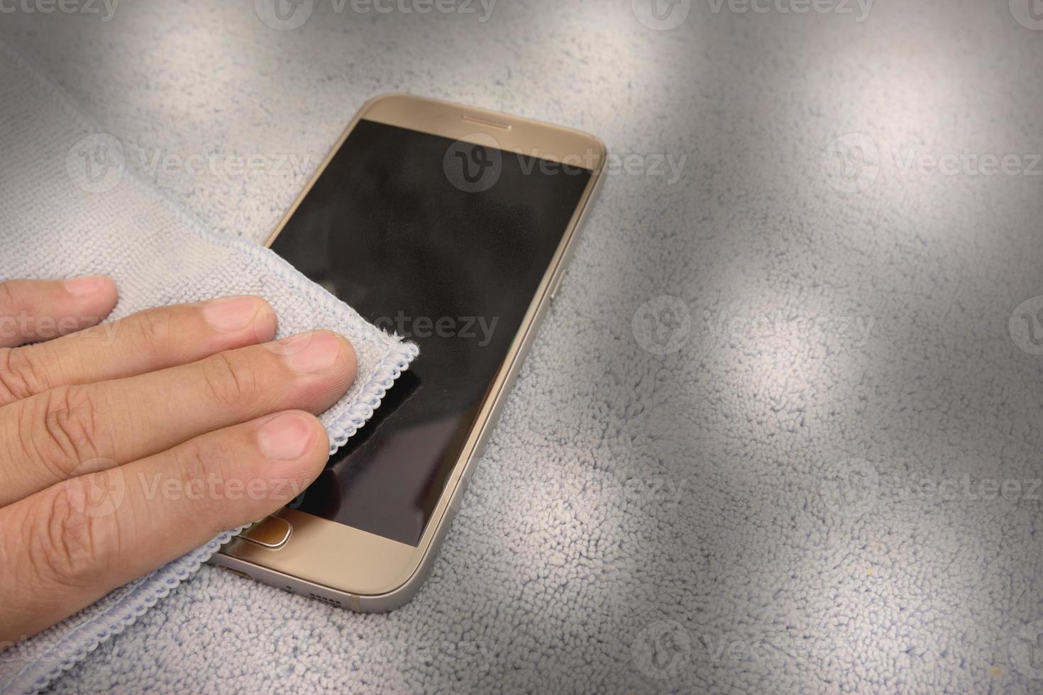 smartphone cleaning dirty screen with blue microfiber fabric photo