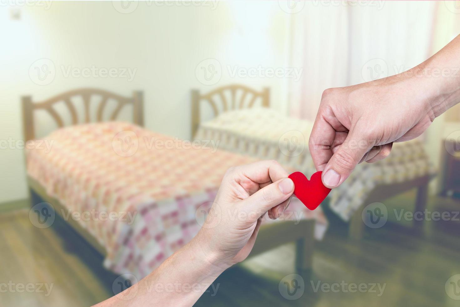 mano sujetando en forma de corazón con dormitorio borroso foto