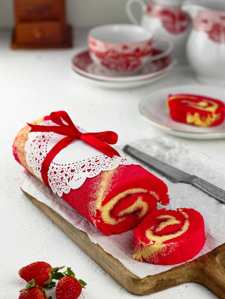 Strawberry Sponge Roll served on a wooden plate photo